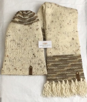 Item # 908 - Unisex Accessory -Material: 100% Acrylic Yarn, Custom Riveted Faux Leather Tags Construction: Double Layered Knit Scarf and Beanie Color(s): Aran Tweed and Toasted Almond Size: OS Stretchable