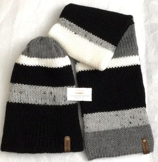 Item # 913 - Unisex Accessories Material: 100% Acrylic Yarn, Custom Riveted Faux Leather Tags Construction: Double Layered Knit Scarf and Beanie Color(s): Tweed, Gray, Black and White Size: OS Stretchable